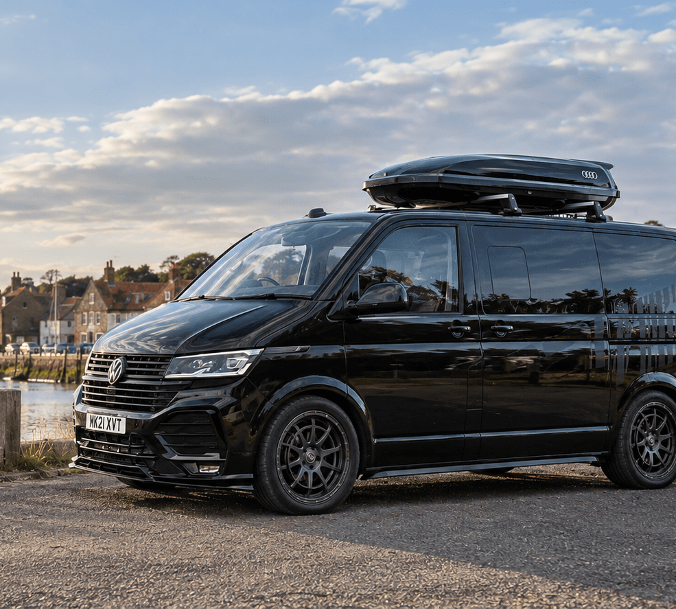 VW Transporter campervan with side windows beside a harbour